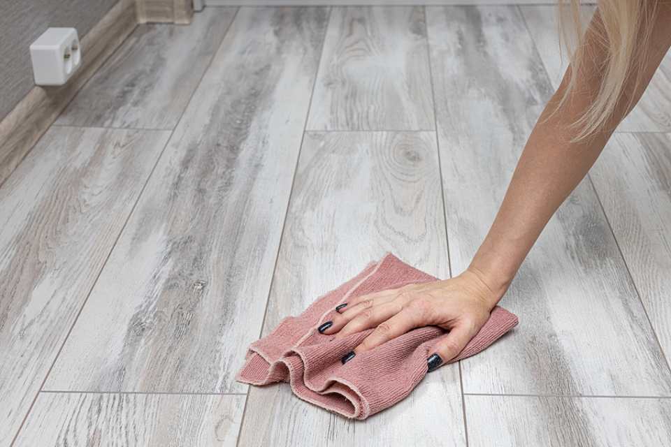 woman cleaning grey look laminate plank